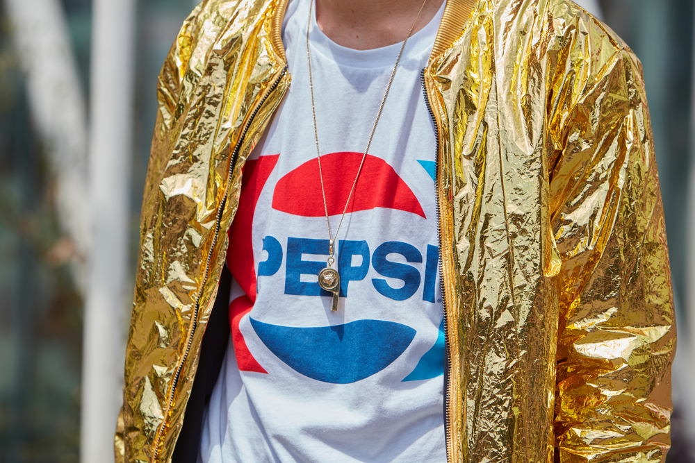 Shutterstock_442337635 Man poses for photographers with shiny golden jacket and Pepsi shirt before Jil Sander fashion show, Milan Men's Fashion Week street style on June 18, 2016 in Milan.