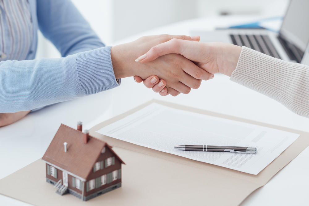 Shutterstock_ 580092196 Real estate broker and customer shaking hands after signing a contract: real estate, home loan and insurance concept