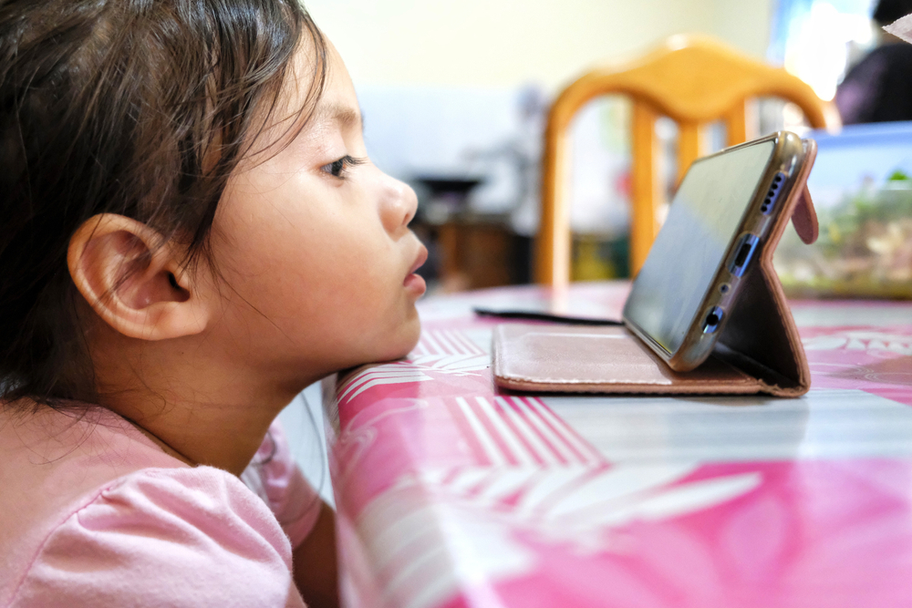 Shutterstock_1484572661 Young kids watching a video in smartphone gadget