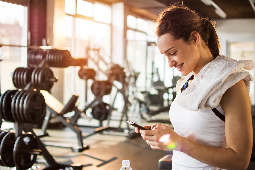 Shutterstock_397877713 Active girl with smartphone listening to music in gym.