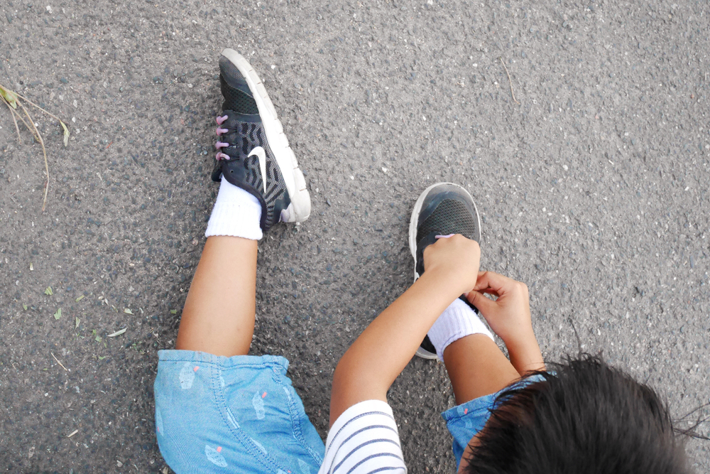 Shutterstock_1356579533 Top view of Asian child boy wearing a Nike 's sneakers shoes at the field. Kid and sport concept.