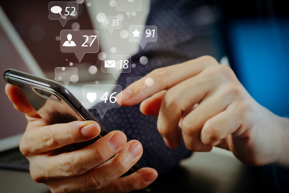 Shutterstock_ 1109787086 Social media and Marketing virtual icons screen concept.close up of businessman hand working with mobile phone and laptop and digital tablet computer in modern office