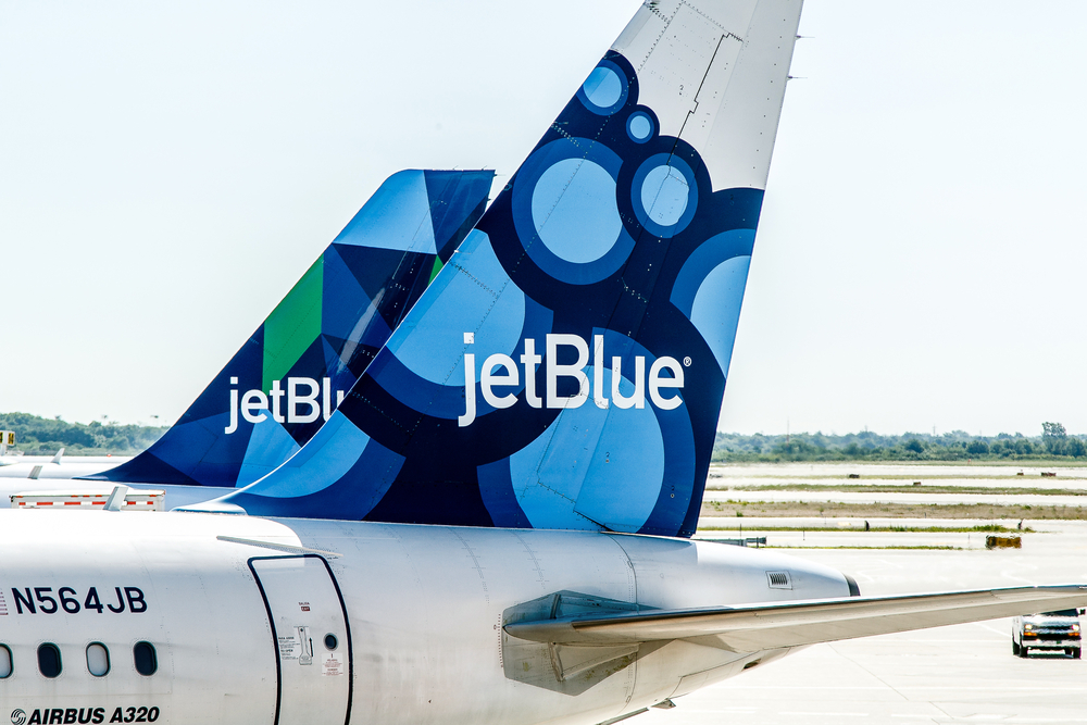 Shutterstock_674776387 Two JetBlue airplanes are parked by the gates awaiting passenger boarding.