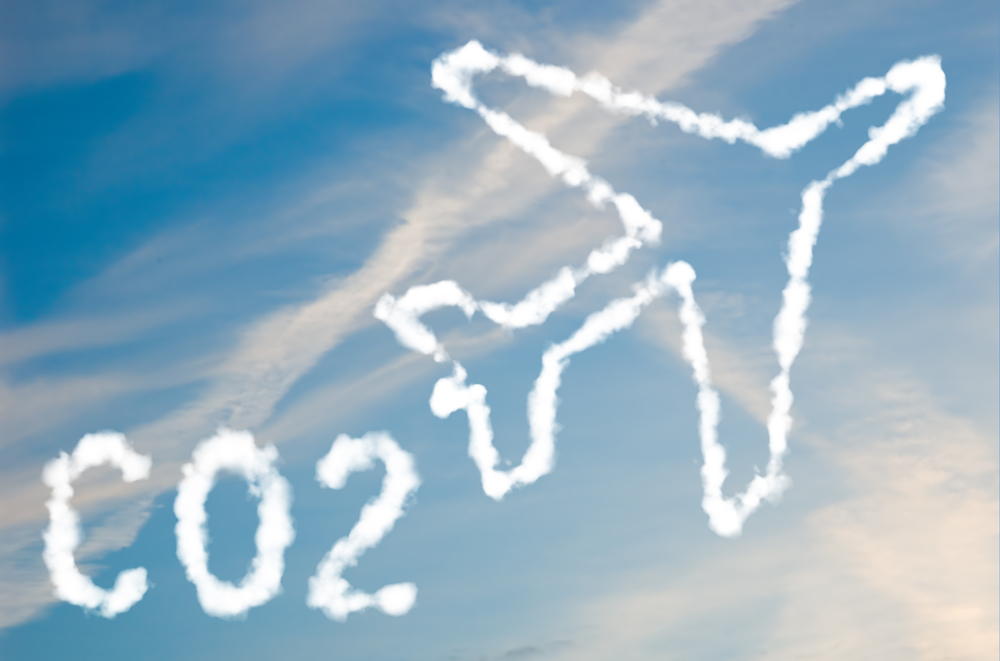 Shutterstock_48670516 An illustration of an airplane with the text CO2 made up of white puffy clouds to represent environmental issues or carbon footprint.