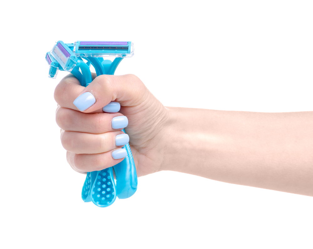 Shutterstock_1350332483 Razor in hand beauty body care on white background isolation