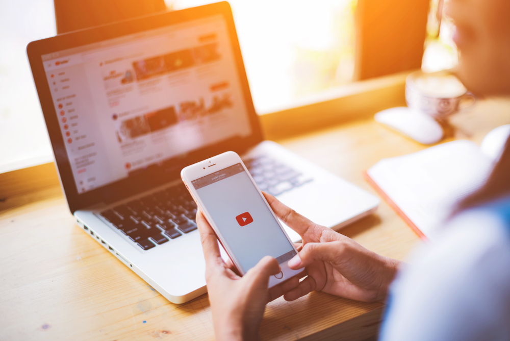 shutterstock_1018468075  Singapore.February, 2018:A Woman holding iPhone with video service YouTube on the screen. iPhone was created and developed by the Apple inc.