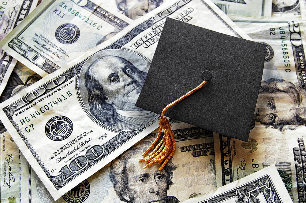 Shutterstock_398418100  Miniature graduation cap on hundred dollar bills