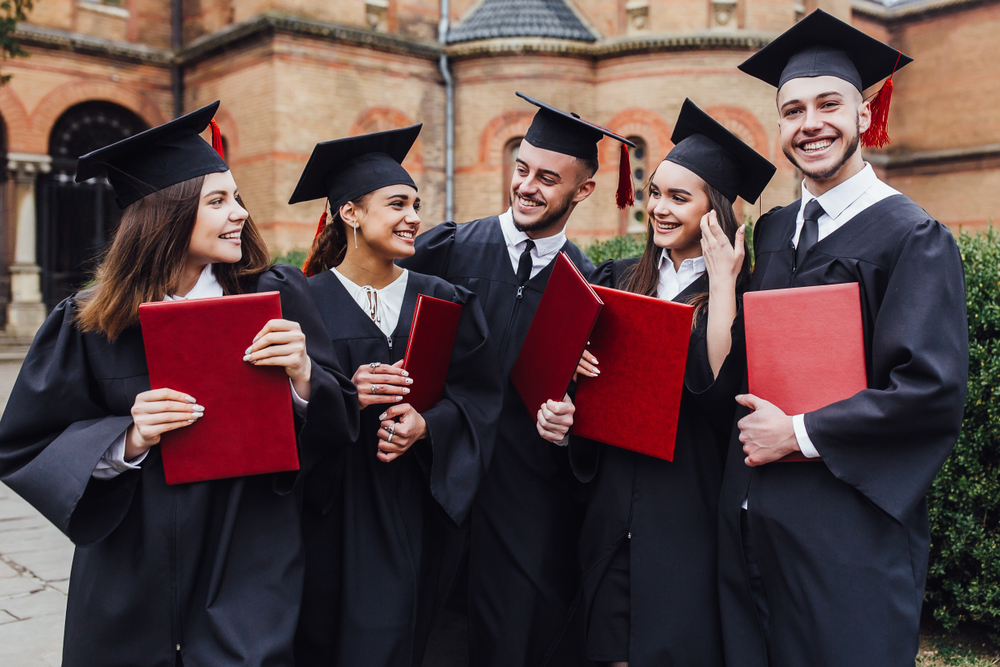 Shutterstock_1382310041  Graduates embrace, enjoy and look at the camera on the graduation ceremony!