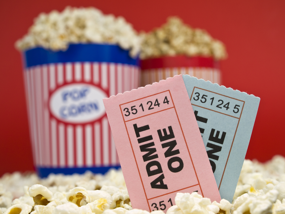 Shutterstock_27060235 Two popcorn buckets over a red background. Movie stubs sitting over the popcorn.