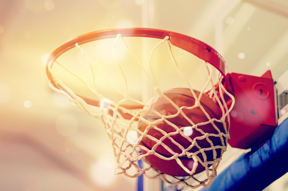 Shutterstock_1489878983 Orange basketball ball flying into the basketball hoop