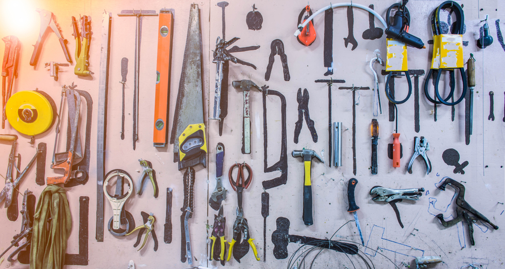 Shutterstock_1021698436  Old tools hanging on wall in workshop.Something's gone. Tools concept