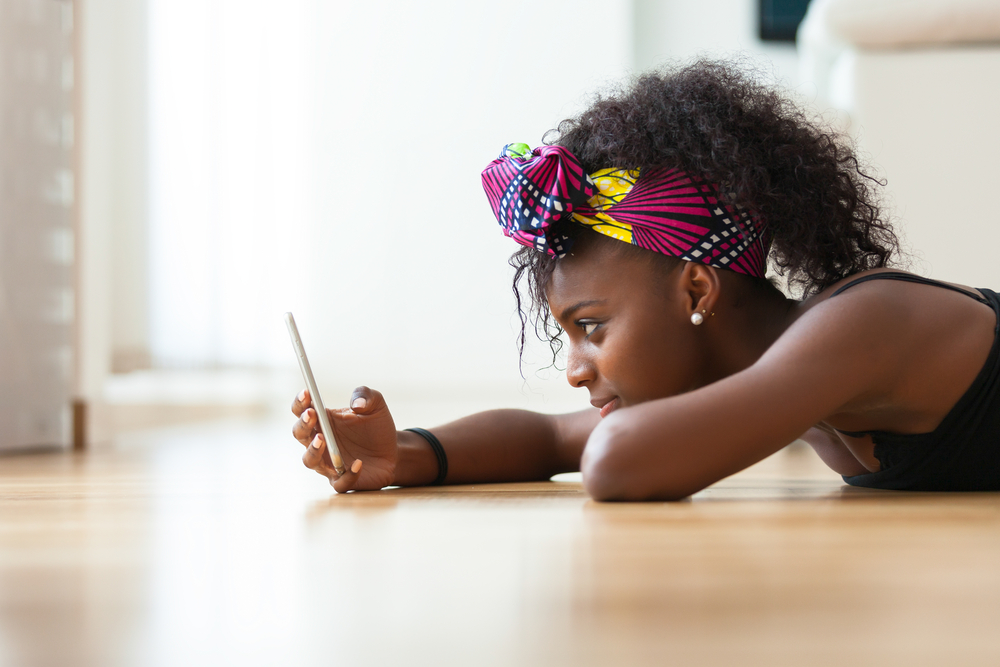 Shutterstock_323884478 African American woman sending a text message on a mobile phone - Black people