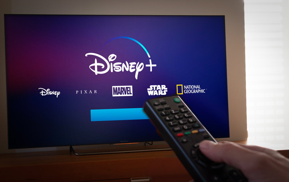 Shutterstock_1272496885 Barcelona, Spain. Jan 2019: Man holds a remote control With the new Disney+ screen on TV. Disney+ is an online video streaming subscription service.Illustrative