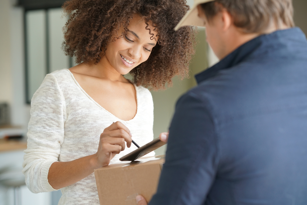 Shutterstock_513792328 Mixed race woman receiving package from delivery man