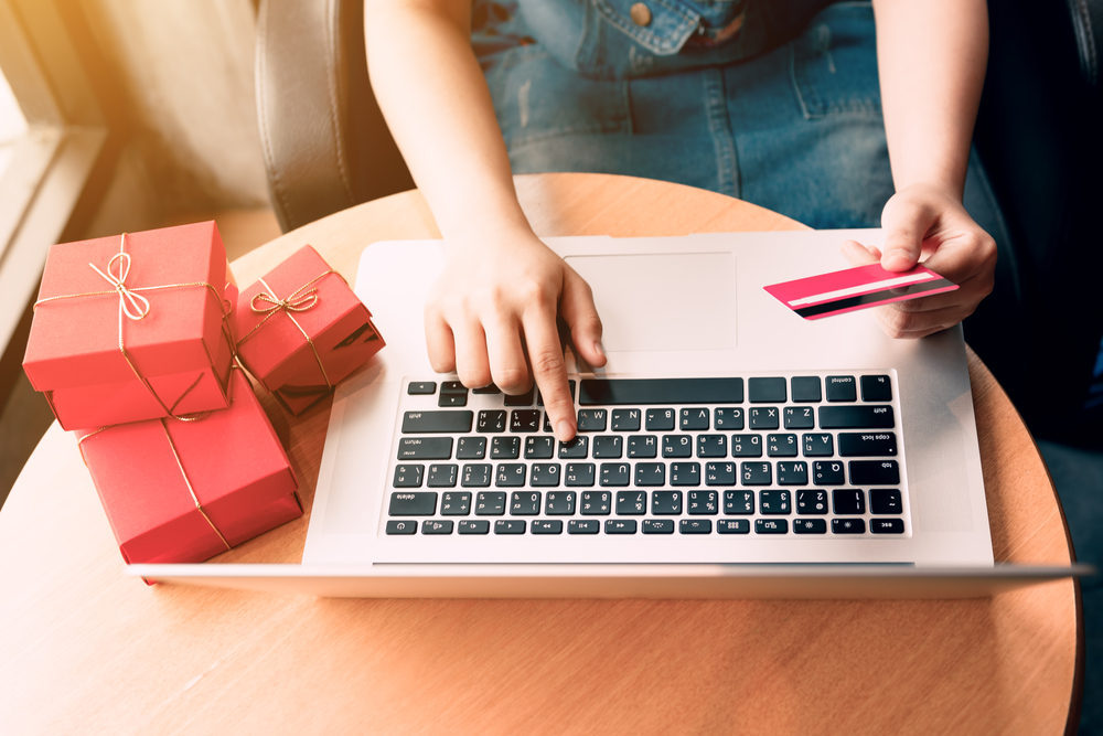 Shutterstock_726760150 Top view of woman hand holding credit card and doing shopping online near window at home.