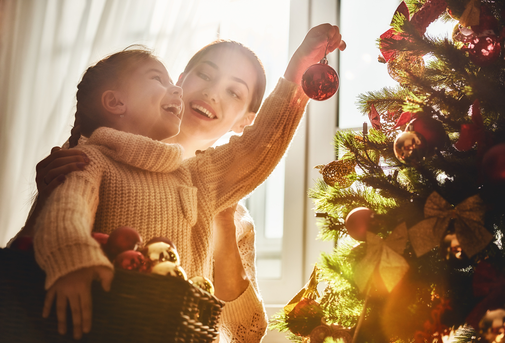 Shutterstock_519972937 Merry Christmas and Happy Holidays! Mom and daughter decorate the Christmas tree indoors. The morning before Xmas. Portrait loving family close up.