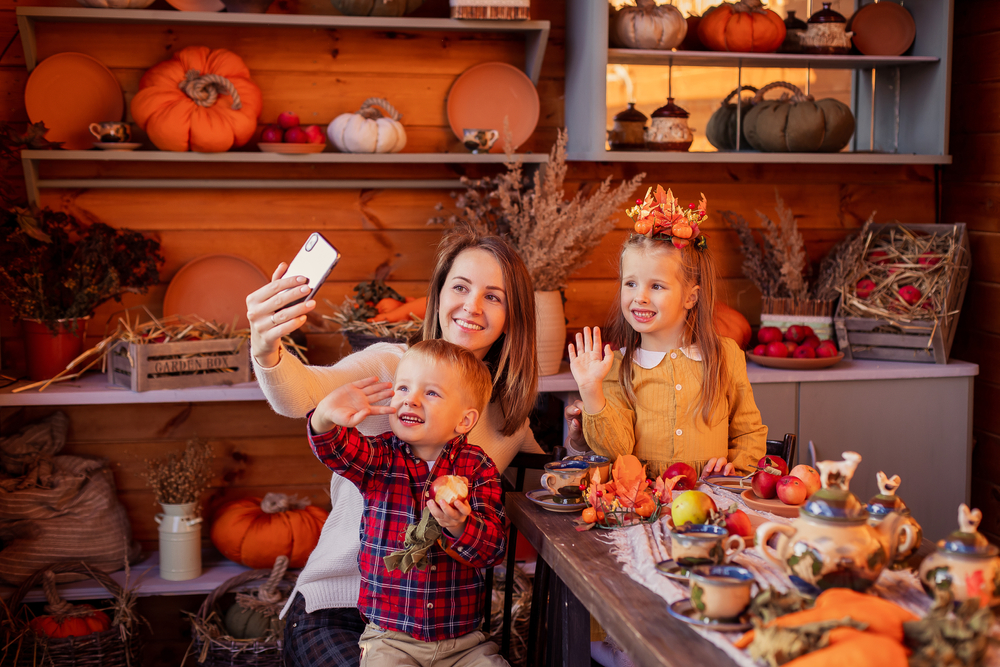 Shutterstock_1829187983 Family congratulates friends on Thanksgiving online. Video chatting with friends new normal. Festive dinner remotely by phone on a smartphone. Social distance pandemic covid-19. Celebrating tradition