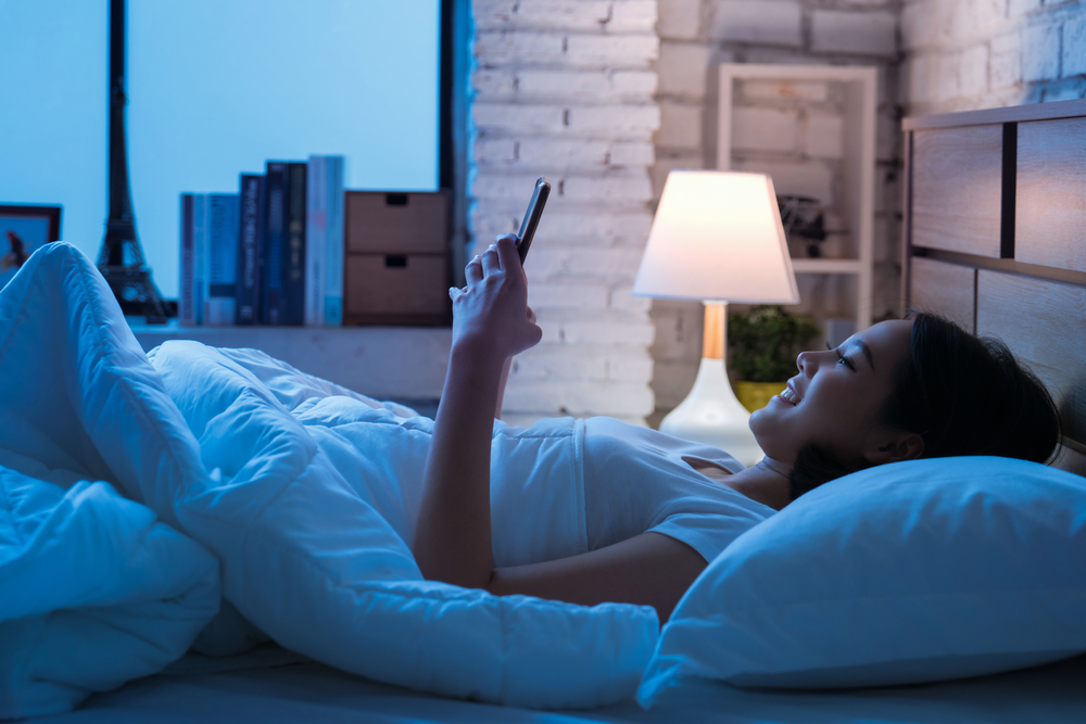 Shutterstock_736958713 Asian women are using the smart phone on the bed before she sleeping at night. Mobile addict concept.