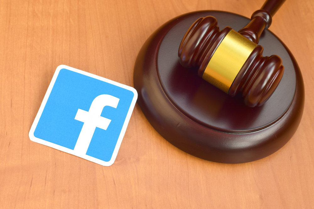 Shutterstock_1698112588 Facebook paper logo lies with wooden judge gavel. Entertainment lawsuit concept