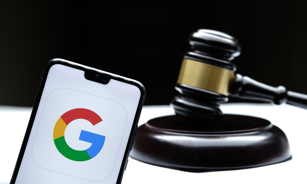 Shutterstock_1875389428 Stafford, United Kingdom - December 15 2020: Google logo seen on the smartphone placed next to the judges gavel. Concept for a lawsuit, legal case, antitrust and fine. Real photo, not a montage.