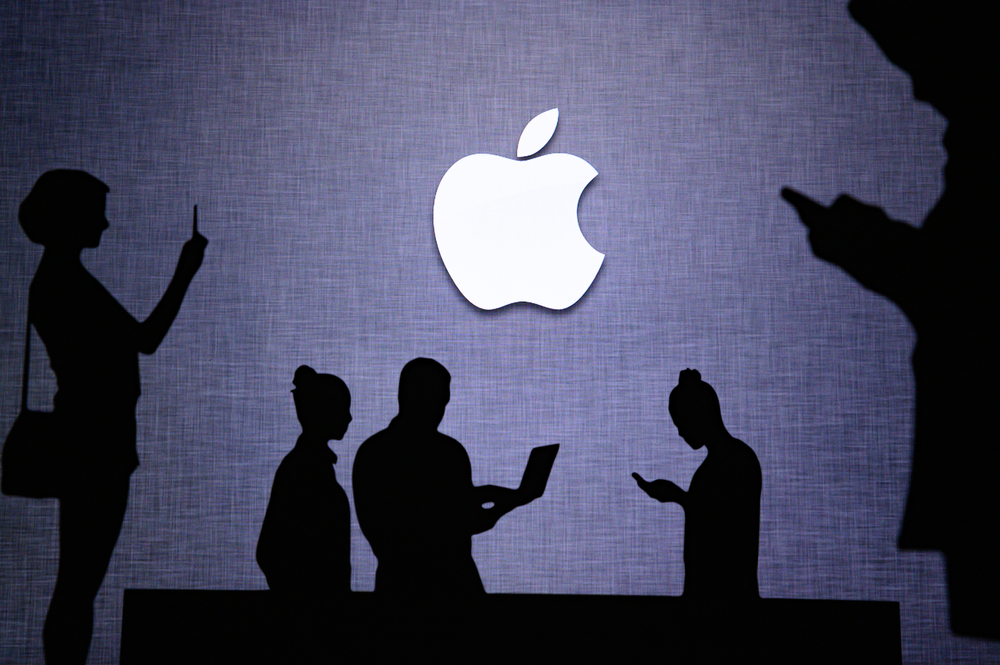 Shutterstock_1757133131 NEW YORK, USA, 25. MAY 2020: Apple American multinational technology company Group of business people chat on mobile phone and laptop. Company logo on screen in background