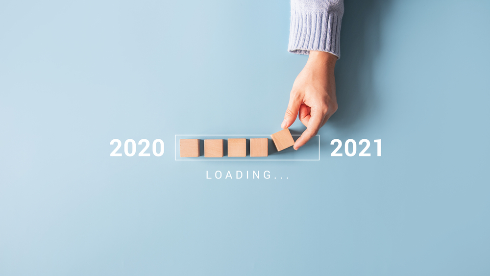 Shutterstock_1831823293 Loading new year 2020 to 2021 with hand putting wood cube in progress bar.