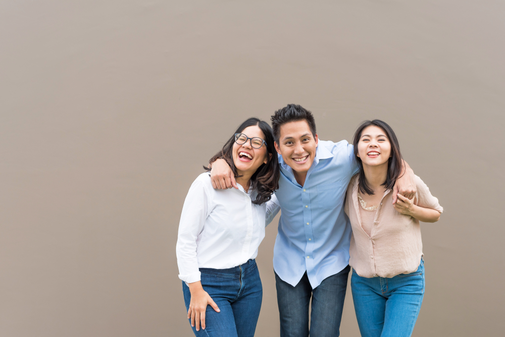 Shutterstock_1039272712 Group of happy three asian friends in casual wear standing laugh and having fun together