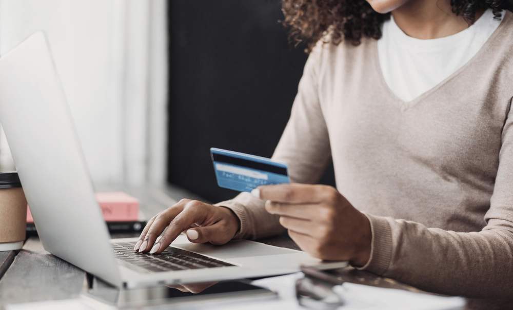 Shutterstock_1840890145 Online shopping. Young woman holding credit card and using laptop at home. Payment online, e-commerce, internet banking, spending money, ordering delivery, business, finance concept