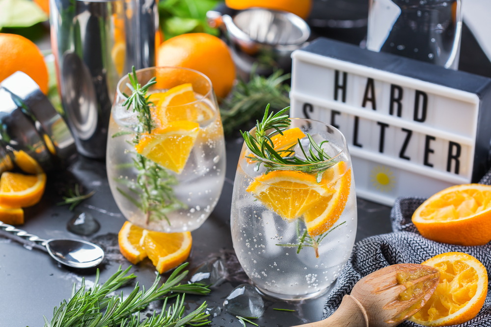 Shutterstock_1933047041 Hard seltzer cocktail with orange, rosemary and bartenders accessories