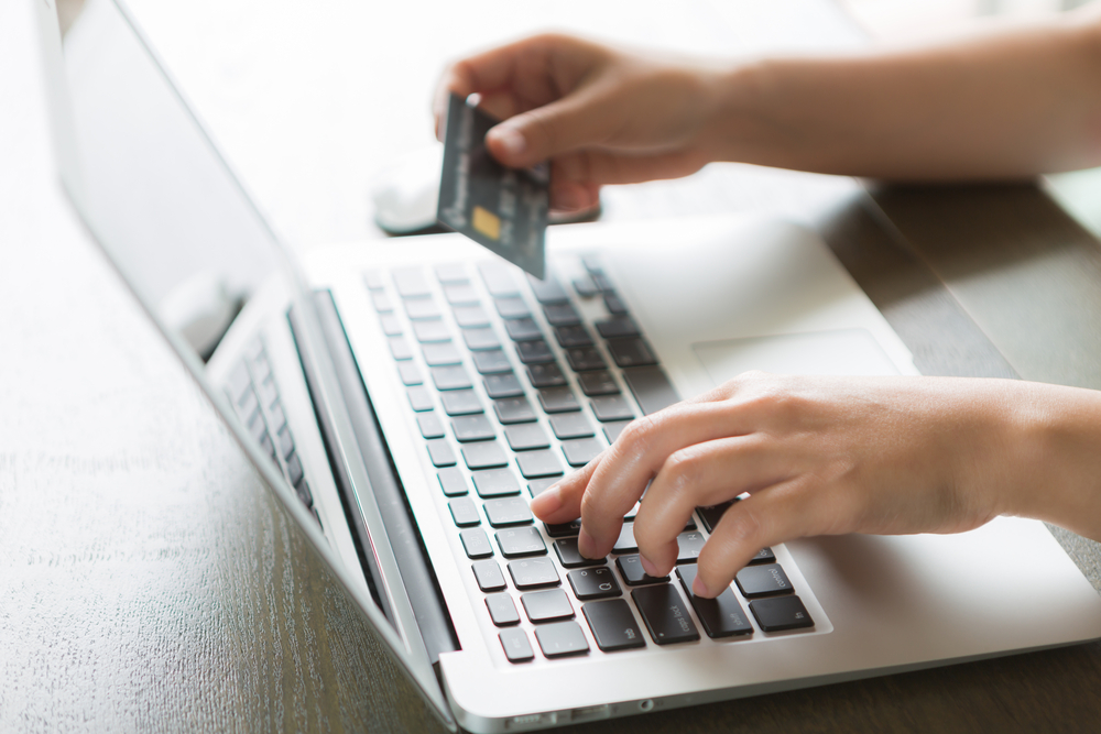 Shutterstock_229253272 Hands holding a credit card and using laptop computer for online shopping